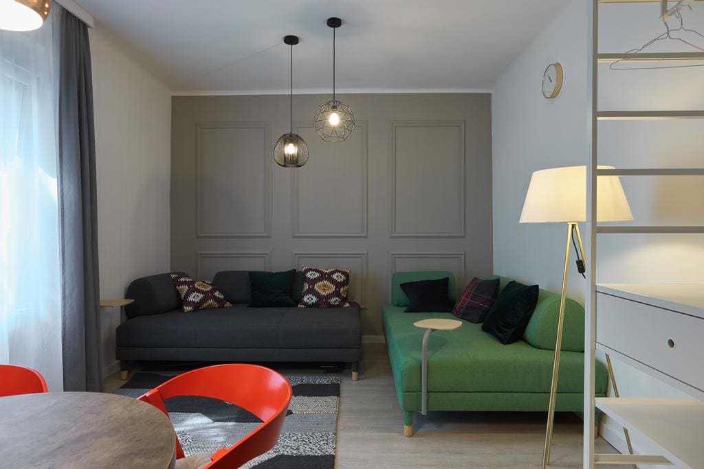 7Domb második apartman — szürke és zöld kanapék, piros szék, lambéria-fal