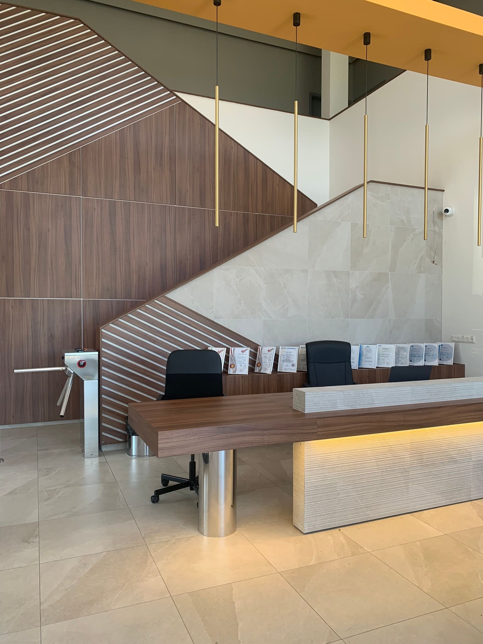 CAADEX recepciós pult — dió csíkos akcentus, travertin hátlap, sárgaréz függőleges függesztékek, rozsdamentes acél támasztóláb, fémvázas asztal